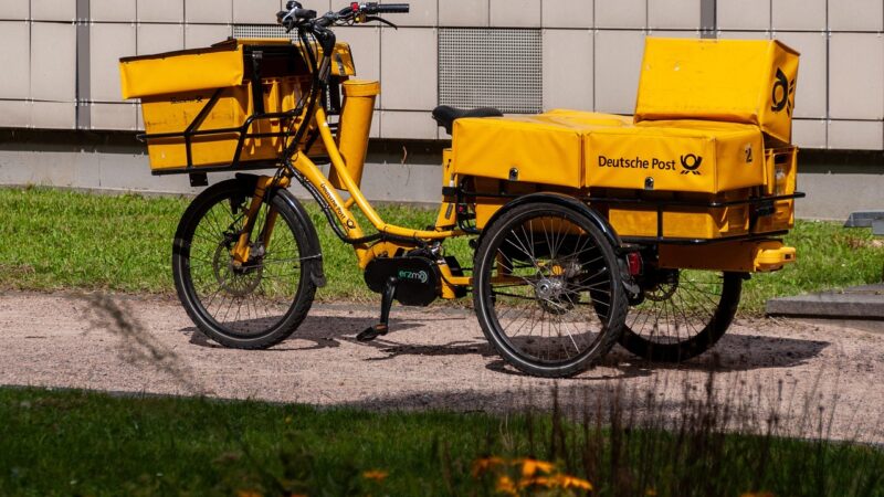 Gele bezorgfiets van Deutsche Post met fietstassen.